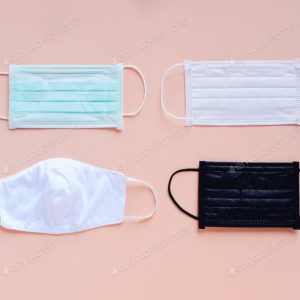 Four different colored face masks on a light pink background.