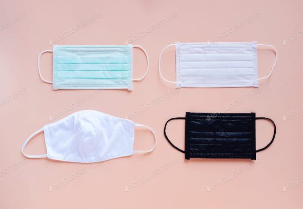 Four different colored face masks on a light pink background.