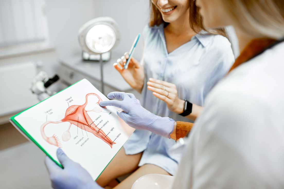 Doctor explaining female reproductive anatomy to a patient with a diagram.