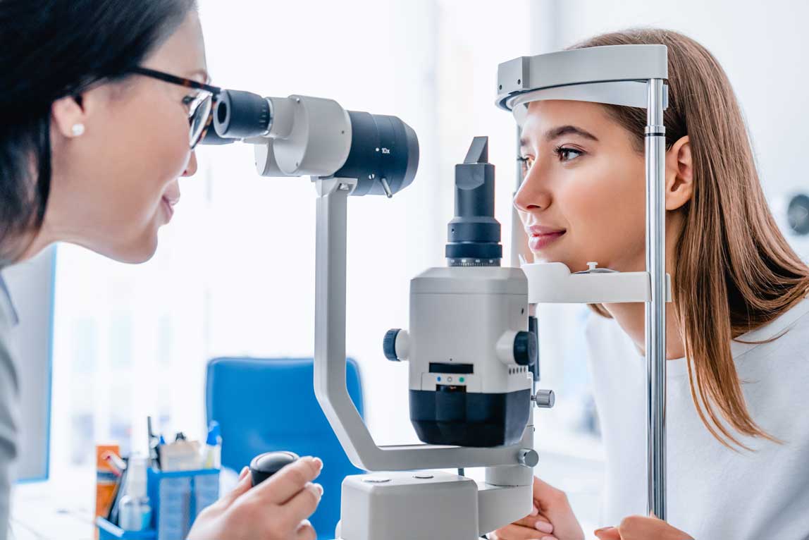 Woman undergoing an eye examination with an ophthalmologist using a slit lamp.